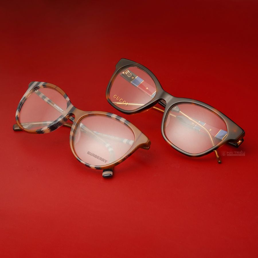 2 chiếc kính mắt mèo của Burberry đang được để trên chiếc bàn đỏ
