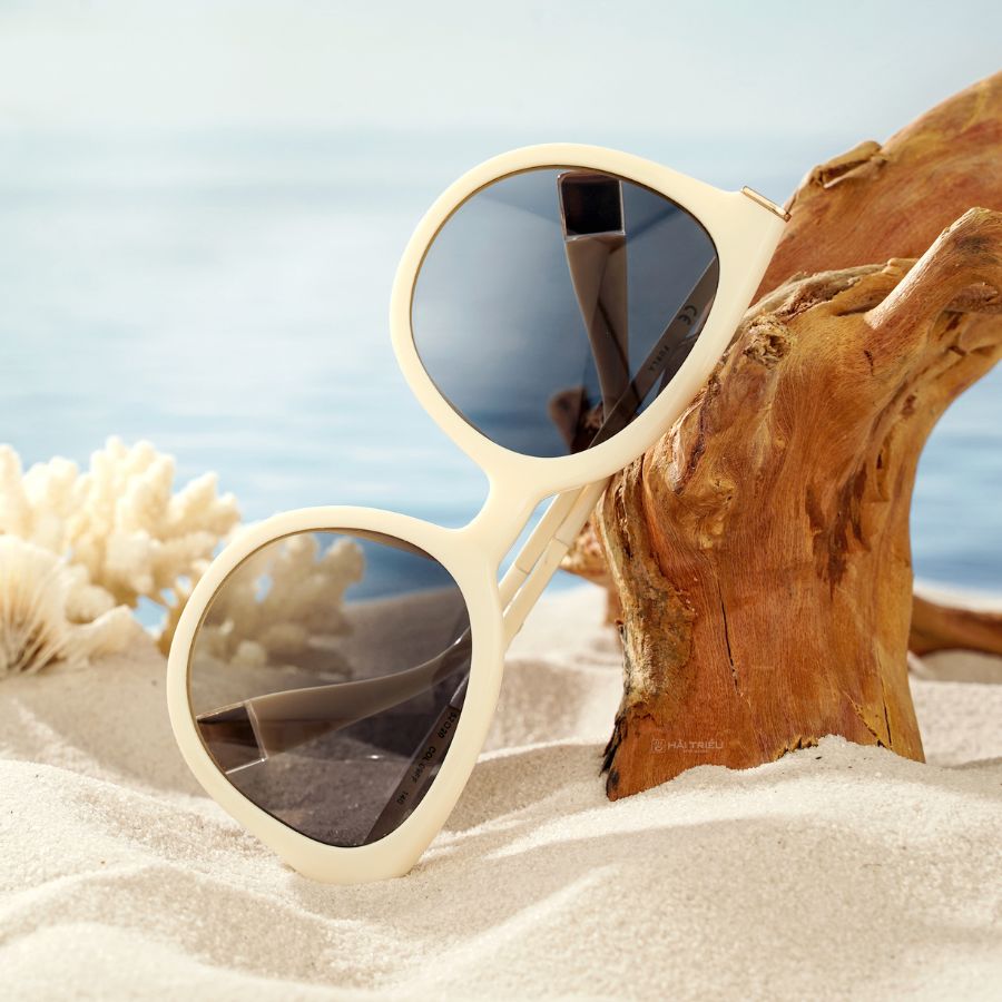 Chiếc kính mát mắt mèo viền trắng đang được bày trí trên bãi cát